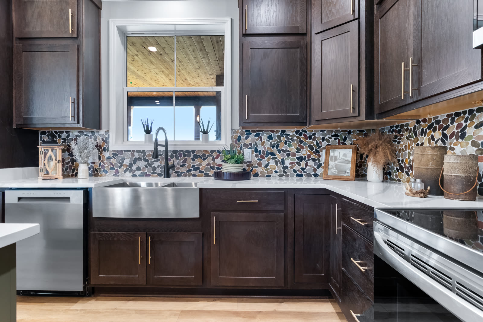Kitchen sink under a window with dark wood cabinets